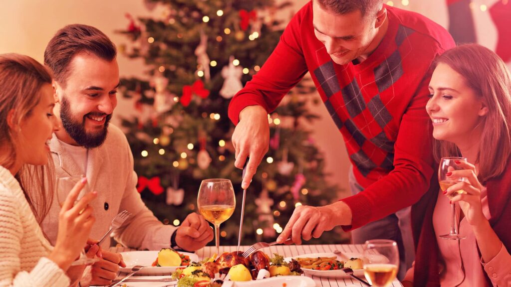 O Natal é uma época mágica, repleta de alegria, amor e celebração em família. No entanto, a preparação para a ceia natalina pode se tornar um desafio financeiro. Com um planejamento inteligente e algumas escolhas criativas, é possível desfrutar de um delicioso banquete sem comprometer o orçamento. Neste artigo, exploraremos dicas práticas para economizar na ceia de Natal, desde o planejamento até as escolhas de ingredientes acessíveis. Confira! Ceia de Natal: Planeje sua lista de compras com inteligência O segredo para uma ceia de Natal econômica e deliciosa começa com um planejamento cuidadoso. Criar uma lista de compras detalhada é essencial para evitar gastos desnecessários e garantir que você tenha tudo o que precisa. Vamos conferir o passo a passo de como elaborar essa lista com eficiência! 1. Faça um levantamento de pratos desejados: Comece pensando nos pratos que gostaria de incluir na ceia. Considere opções que agradem aos convidados e representem a tradição natalina da sua família. Isso pode incluir pratos principais, acompanhamentos, saladas, sobremesas e bebidas. Anote todas as ideias para ter uma visão geral do que será necessário. 2. Considere o número de convidados: Antes de definir a quantidade dos ingredientes, leve em conta o número de convidados. Uma lista de convidados ajuda a determinar as porções necessárias e evita compras excessivas. 3. Estime seu orçamento: Defina um orçamento realista para a ceia de Natal. Considere todos os elementos, como ingredientes, decorações e bebidas. Isso ajudará a evitar gastos excessivos e permitirá que você se concentre em opções mais econômicas. 4. Priorize ingredientes versáteis: Ao escolher pratos, opte por receitas que compartilhem ingredientes comuns. Isso reduz o número de itens na sua lista de compras, pois você pode usar esses ingredientes em várias receitas. 5. Verifique os itens que já tem em casa: Antes de sair para as compras, dê uma olhada nos itens que já possui. Certifique-se de que não está comprando algo que já tem. 6. Faça uma lista detalhada por categoria: Separe sua lista de compras em categorias, como produtos frescos, produtos secos, congelados, bebidas e itens de decoração. Organizar a lista dessa maneira facilita a ida ao supermercado e evita esquecimentos. 7. Esteja atento a promoções e descontos: Antes de finalizar a lista, dê uma olhada nos folhetos de supermercados e lojas locais. Se houver promoções ou descontos em itens que você planeja comprar, ajuste sua lista para aproveitar essas ofertas e economizar ainda mais. 8. Ajuste a lista conforme o orçamento: Durante as compras, esteja preparado para fazer ajustes conforme necessário. Se um item estiver além do seu orçamento, procure alternativas mais baratas. 9. Compre com antecedência: Evite compras de última hora, que geralmente resultam em gastos desnecessários. A compra antecipada permite que você aproveite promoções e descontos, contribuindo para uma economia significativa. 10. Faça Você Mesmo (DIY): Dê um toque pessoal à ceia preparando alguns itens em casa. Molhos, pães e sobremesas feitos em casa não apenas são mais econômicos, mas também adicionam um toque caseiro especial à refeição. 11. Pesquise preços online: Antes de ir às compras, pesquise os preços dos itens desejados em diferentes lojas online. Muitas vezes, você pode encontrar promoções exclusivas na internet. 12. Aproveite cupons de desconto: Utilize cupons de desconto disponíveis em aplicativos ou sites especializados. Muitas lojas oferecem códigos promocionais que podem resultar em economias significativas. 13. Explore serviços de entrega: Considere a praticidade de serviços de entrega, como compras online ou delivery de supermercados. Isso pode economizar tempo e permitir que você evite compras impulsivas durante a visita física à loja. 14. Divida os custos com os convidados: Combine com os convidados sobre dividir os custos da ceia. Liste o que precisa, use aplicativos para calcular. Seja transparente e permita opções criativas. Mantenha o espírito leve e colaborativo. Ao seguir essas dicas, você estará preparado para planejar uma ceia de Natal econômica, sem abrir mão do sabor e da tradição. Escolhas econômicas e saborosas para a Ceia de Natal Para garantir uma ceia deliciosa sem comprometer o orçamento, considere estas sugestões de trocas mais econômicas: 1. Frango assado ao invés de aves mais caras: Prefira o frango de granja em vez das aves mais caras. Assado com temperos e ervas, ele pode se destacar como peça central da mesa. 2. Massas e vegetais como opções principais: Escolha pratos de massa, como lasanha de vegetais ou canelones recheados, como principais na ceia. Experimente receitas criativas com legumes da estação para adicionar cores vibrantes e muito sabor. 3. Sobremesas simples e saborosas: Substitua sobremesas caras por opções mais simples e igualmente deliciosas. Um bolo caseiro decorado com frutas da estação ou um pudim de pão podem ser alternativas econômicas e encantadoras. 4. Bebidas refrescantes e econômicas: Elabore bebidas não alcoólicas refrescantes, como ponche de frutas, limonada ou chás gelados aromatizados. Essas opções são mais econômicas do que vinhos e champanhes. Se optar por álcool, escolha opções mais acessíveis ou crie coquetéis com ingredientes econômicos. 5. Utilize ingredientes locais e da estação: Compre ingredientes frescos e locais, que geralmente são mais acessíveis e estão no auge de sabor e qualidade. A chave para uma Ceia de Natal econômica está em aproveitar ingredientes acessíveis e transformá-los em pratos que encantem os paladares dos seus convidados. Decoração natalina sem pesar no bolso Decorar para a ceia de Natal pode ser econômico e encantador ao mesmo tempo. Considere estas dicas para criar uma decoração festiva sem comprometer o orçamento: ● Utilize ramos de pinheiro, folhas de eucalipto ou até mesmo galhos secos para criar arranjos simples e elegantes. ● Velas são opções econômicas e proporcionam uma luz suave e acolhedora. Escolha velas brancas ou vermelhas para manter a paleta de cores natalinas. ● Reutilize enfeites de anos anteriores ou peça às crianças da família para criar decorações caseiras, tornando o ambiente ainda mais especial. ● Utilize guardanapos de pano simples amarrados com fitas vermelhas ou verdes para adicionar um toque clássico à mesa. ● Pratos e talheres coordenados, mesmo que simples, criam uma apresentação elegante. Não é necessário investir em conjuntos caros. Lembre-se, a beleza está nos detalhes, e você pode criar uma decoração natalina inesquecível sem gastar muito! 